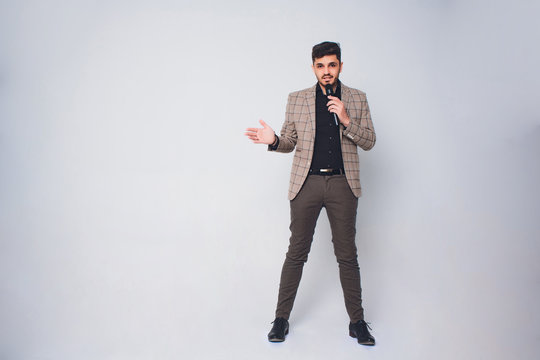 Showman interviewer with emotions. Young elegant man holding microphone against white background.Showman concept.