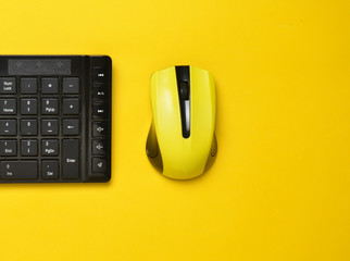 Wireless mouse and keyboard isolated on yellow pastel background. Top view, minimalist trend.