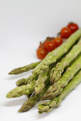 Green asparagus and red tomatoes on white background