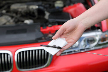 Auto serwis,miarka pomiaru poziomu oleju w dłoniach mechanika na tle silnika w samochodzie. - obrazy, fototapety, plakaty