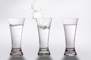 three glasses and a splash of water on a gray background