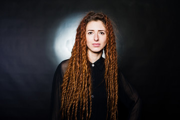Studio shoot of girl in black with dreads at black background.