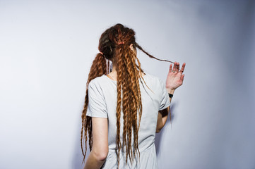 Studio shoot back of girl in gray dress with dreads on white background.