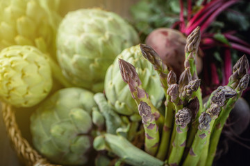 A still life of artichokes and asparagus on the rustic textured background Top view toned