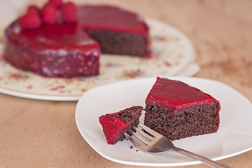 A morsel of chocolate cake with red raspberry glaze.
