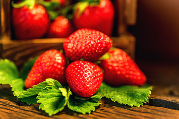 Fresh strawberries with leaves in wooden box close