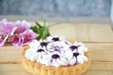 Berry mini tarts with the plate of berries over a white rustic wooden background, top view