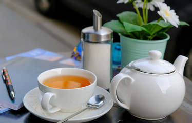 tea cup with kettle, sugar and plant on table in cafe outdoor