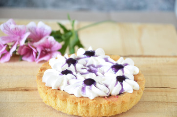Berry mini tarts with the plate of berries over a white rustic wooden background, top view
