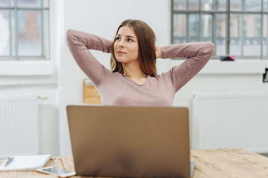 Young relaxed woman sitting in front of laptop