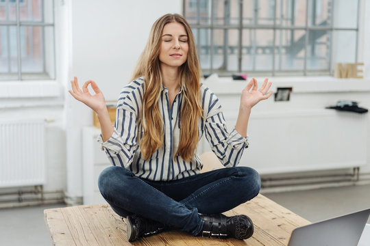 Young woman sitting meditating in the office