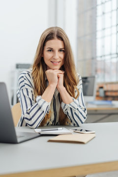 Young smiling woman sitting at desk in office
