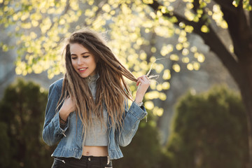 Smiling portrait of fashionable woman with dreadlocks at springtime