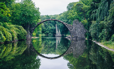 Rakotzbrücke (Rakotzbrucke) auch bekannt als Teufelsbrücke in Kromlau, Deutschland. Die Spiegelung der Brücke im Wasser erzeugt einen vollen Kreis.