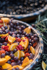 red kalamata olives marinated in oil decorated with oranges and peppers on display at market