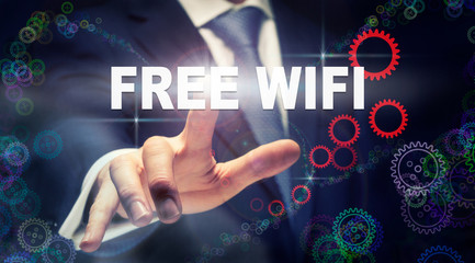 A businessman pressing a Free WiFi business concept on a graphical display of cogs