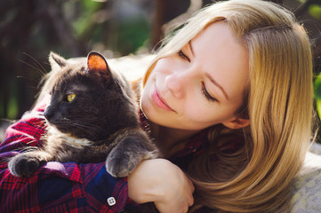 beautiful blonde woman with a cat in nature, bright and sunny. Pets