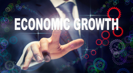 A businessman pressing a Economic Growth business concept on a graphical display of cogs
