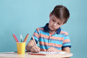 Caucasian boy carefully drawing with colorful pencils.