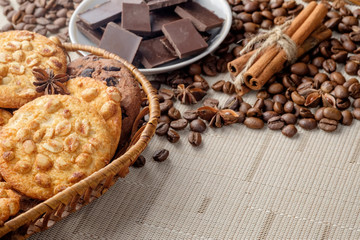Peanut cookies and chocolate chips cookies in wicker basket on light surface and scattered coffee beans near it. Copy space for your text.