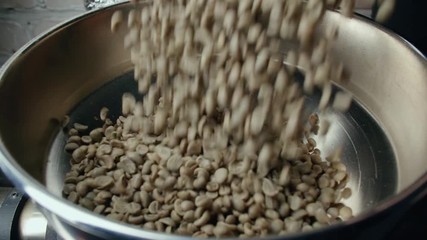 slow motion raw Arabica coffee beans falling into the roaster machine