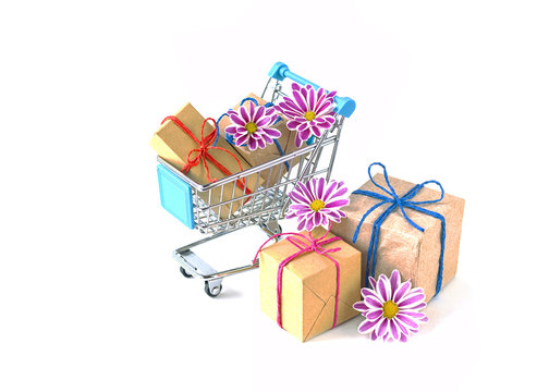 Creative concept of shopping trolley with wrapped gifts on light background. 