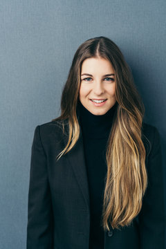 Young woman in polo neck jumper against dark wall