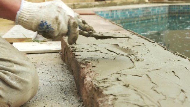 spatula and bucket with mortar on the construction site. the builder finishes the surface with plaster. 4k. pool repair.