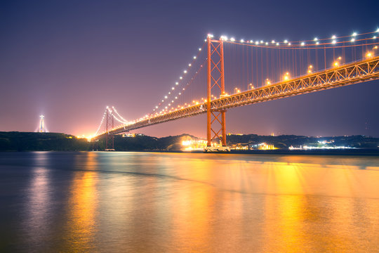 Bridge 25th of April with Christ the King statue in Lisbon. Night lights on the bridge