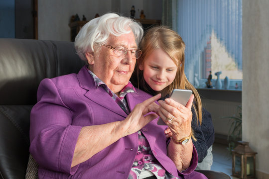 Großmutter, die ihrem Enkelkind etwas lustiges auf ihrem Smartphone zeigt