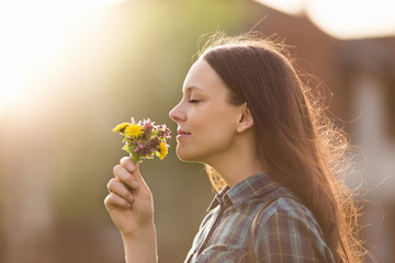 Pretty woman smelling flowers - obrazy, fototapety, plakaty