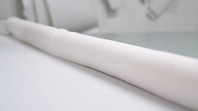 Clothing designer is working with measurements on a studio table. Shot on in 4K UHD . Closeup deploy a skein of white fabric in white and light-colored sewing in slow motion. handmade tailoring of