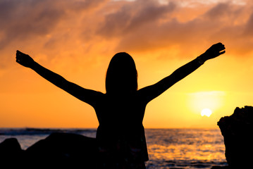 Fototapeta premium Silhouette of girl in the sea watching the sunrise