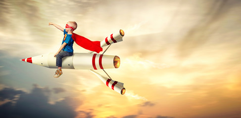Boy in superhero costume fly on a rocket and show super abilities.	