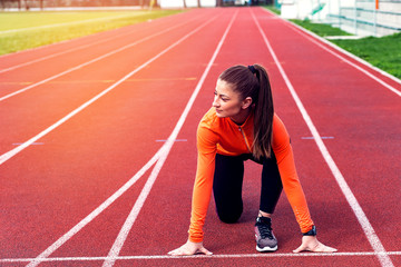 Fototapeta premium Focused sports women in running start position on racetrack