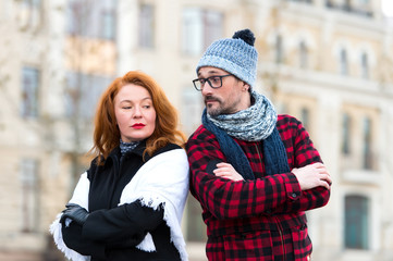 Couple with crossed hand on chest and lean to shoulders looked at each other. Urban couple disagree. Surprised man and offended woman. Red hair lady offended and inquiringly looked man in glasses
