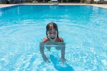 Smiling little girl in an outdoor pool in summer