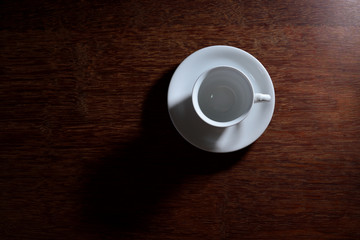 Empty coffee cup with plate on wooden table floor.