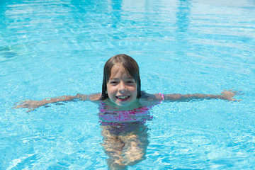 Fototapeta na wymiar Smiling little girl looking at camera in an outdoor pool