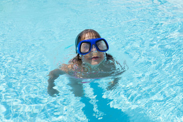 Naklejka premium Little girl with blue diving glasses in an outdoor pool