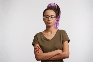 Isolated studio shot of mixed race girl keeps her eyes closed, crossed her hands and think about some problems in her life.