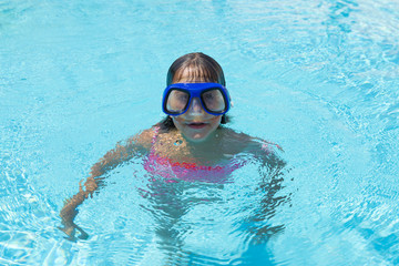 Little girl with blue diving glasses in an outdoor pool