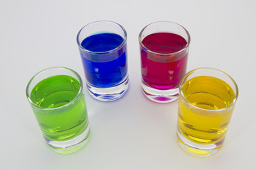 Multicolored glasses of different drinks. Party and holiday celebration concept. Four glasses with a blue, green, yellow and red drink. Isolated on white background.