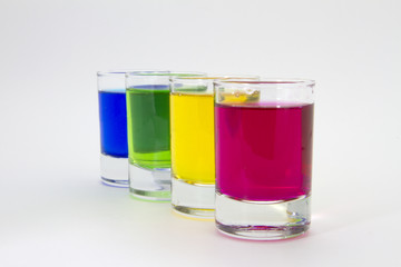 Multicolored glasses of different drinks. Party and holiday celebration concept. Four glasses with a blue, green, yellow and red drink. Isolated on white background.