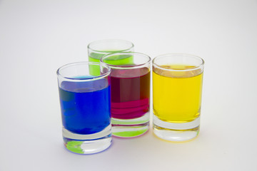 Multicolored glasses of different drinks. Party and holiday celebration concept. Four glasses with a blue, green, yellow and red drink. Isolated on white background.
