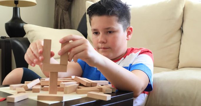 Preteen boy  playing with wooden tower block game  at home