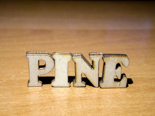 The word 'pine' made of wooden letters. wood inscription on table