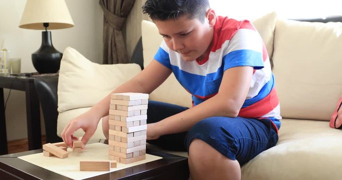 Preteen boy  playing with wooden tower block game  at home