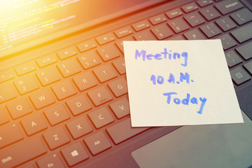 Meeting message concept written post it on laptop keyboard