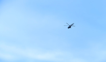 The military helicopter in the blue sky above me high. High in the sky aviation.